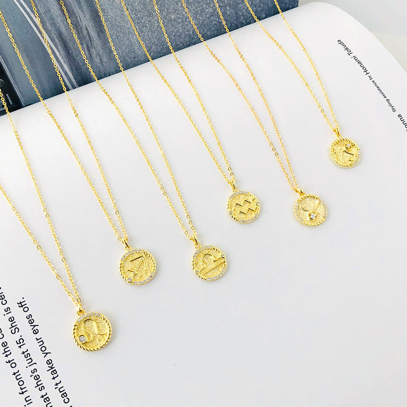 six gold zodiac coin necklaces laying on an open book