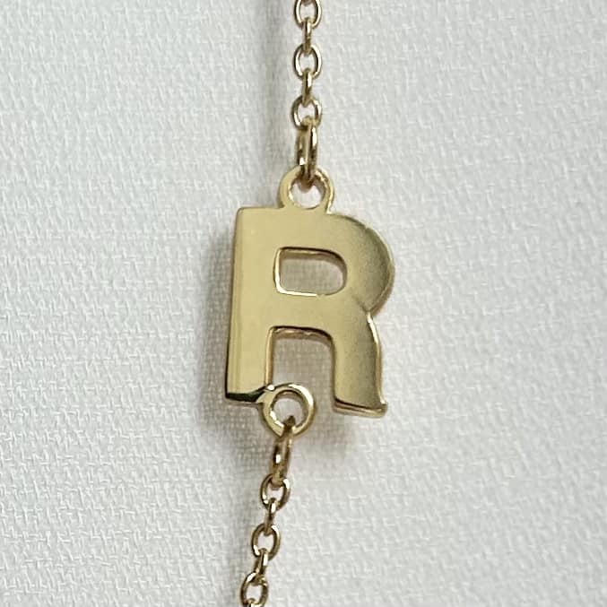 close up of gold initial R on a necklace